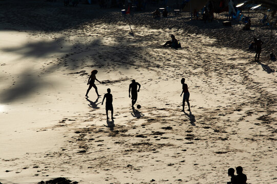 Young people playing soccer on the beach sand