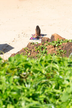 Woman sitting alone on the beach sand looking at the sea