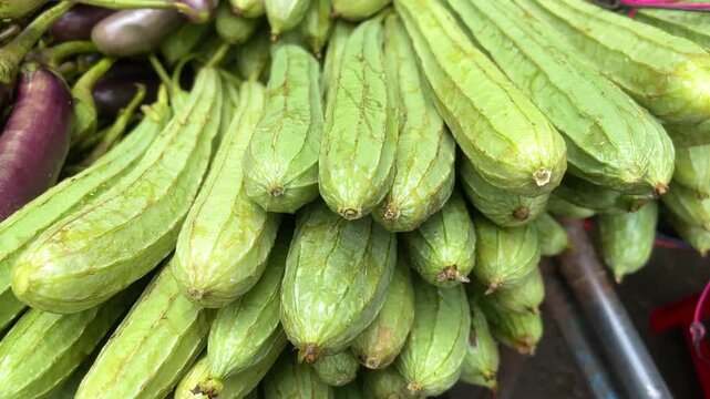 Fresh ridge gourds displayed for sale at a street market in Dhaka, Bangladesh, capturing local vegetable trade and everyday urban market life.