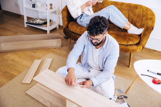 Man assembling flat pack furniture in living room