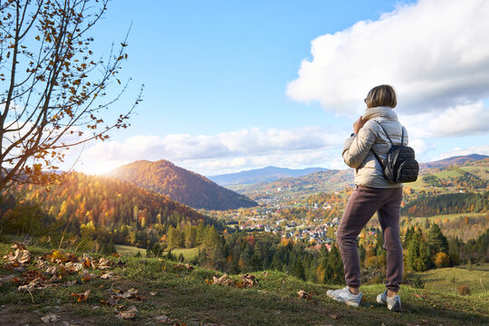 Woman traveler looking at a small mountain village in a valley d