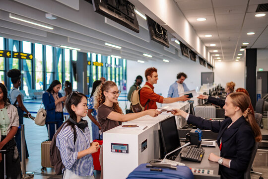 Passengers checking in luggage and passports at airport counter