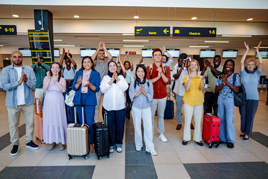 Diverse group of clapping people traveling in airport terminal