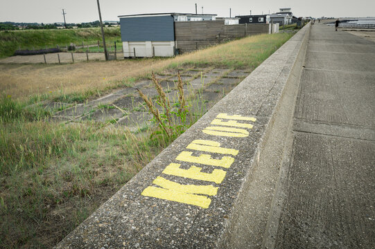 Shallow focus of a newly painted Keep Off stencil seen on a concrete flood and tide wall on the Hunstanton to Heacham coastline in Norfolk, UK.