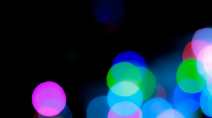 Abstract colorful bokeh lights background with vivid blue green and pink spheres on black backdrop © josh