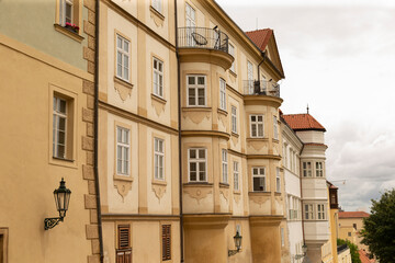 A row of pale yellow historic townhouses featuring curved bay windows, decorative stucco details and small wrought iron balconies. The scene shows multiple © Alena