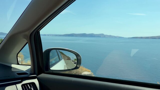Beautiful view of the Adriatic coastline filmed from a moving car. Calm blue sea, distant mountains and a scenic coastal road create a perfect summer road trip atmosphere. Ideal for travel, tourism, v