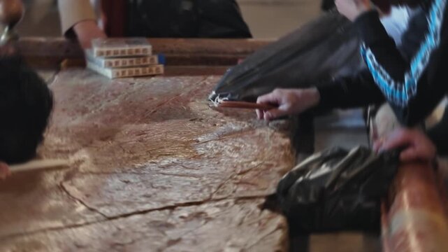 Slow motion footage of a Christian pilgrim's hand lighting a bundle of candles by rubbing them on the holy Stone of Anointing inside the Church of the Holy Sepulchre in Jerusalem, Israel