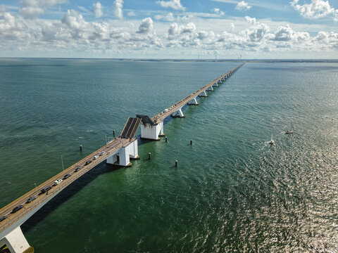 Zeeland Bridge spanning Oosterschelde estuary, bascule section open for sailing boats, traffic waiting on long coastal road