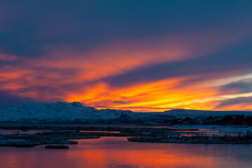 Fototapeta premium Winter sunset over Þingvallavatn in Þingvellir National Park Iceland with colorful reflections snow covered mountains and a tranquil volcanic lake