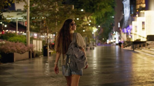 Evening cityscape of Orchard Road in Singapore City with a beautiful female tourist walking beneath illuminated streets bright storefronts and vibrant urban lights in Asia