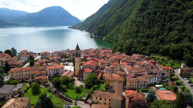 Cinematic Aerial Drone View of Porlezza Italy Lakeside Village on Lake Lugano Swiss Border Iconic Church Tower Surrounded by Lush Green Mountains Authentic Mediterranean Atmosphere Summer 4K Footage
