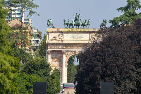 Milan Italy Majestic Triumphal Arch with a Bronze Quadriga Statue, Green Summer Trees. Italian architecture in old city