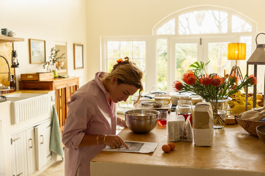 young woman in light filled kitchen using mixing bowl and cooking