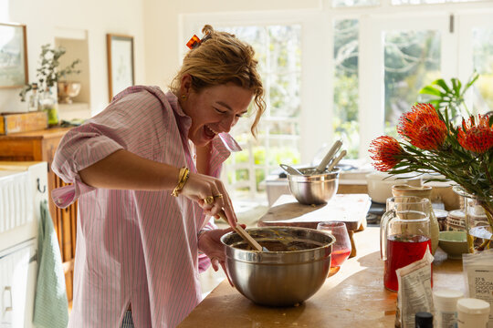 young woman in light filled kitchen using mixing bowl and cooking