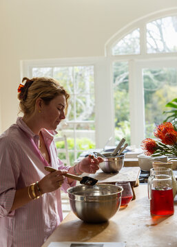 young woman in light filled kitchen using mixing bowl and cooking