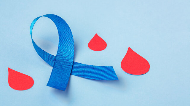 Diabetes Day concept, Blue ribbon and red blood drop on blue background
