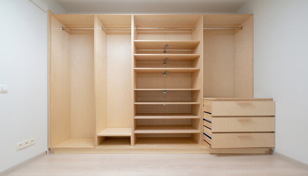 Spacious Custom-Made Empty Light Wood Walk-in Closet and Wardrobe System with Multiple Shelves, Hanging Rods, and Drawers for Home Storage and Organization