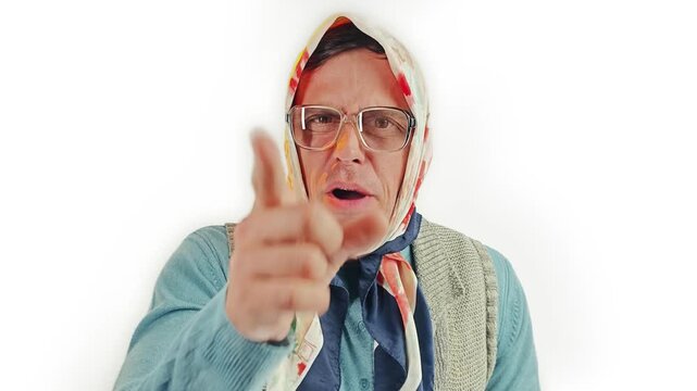 Grumpy old grandmother in a headscarf and glasses scolding at camera
