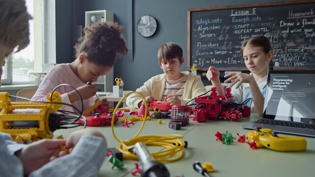 Multiethnic children building and programming robots during STEM class in school. Ideal for promoting STEM education, modern school curriculums, and robotics camps