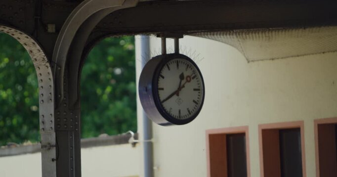 Analog clock hanging from the ceiling of a railway station platform