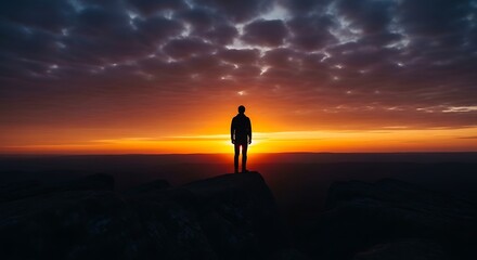 Fototapeta premium Solitary figure silhouetted against dramatic sunset sky.