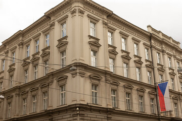 Obraz premium Neoclassical corner building with ornate window pediments and pilasters, painted in beige tones. Tall rectangular windows with white frames