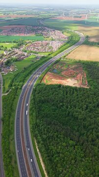 Aerial vertical landscape of a major motorway in the UK snaking its way through countryside into the distance with traffic and copy space