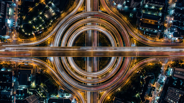 Top view of illuminated highway interchange and city traffic at night.