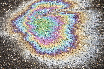 Obraz premium Oil on Pavement Shows Colorful Patterns Under Sunlight in an Urban Setting During Daytime Hours.
