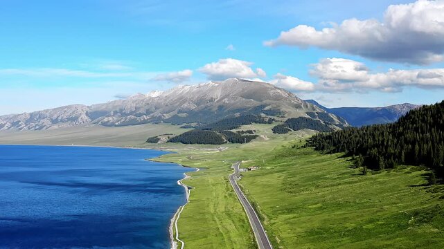 Aerial view of the highway scenery of the Sayram Lake Plateau at the foot of the snow-capped mountains in Xinjiang, China