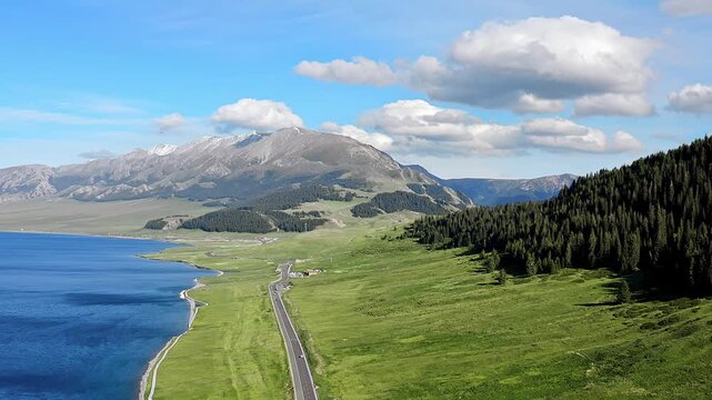 Aerial view of the highway scenery of the Sayram Lake Plateau in Xinjiang, China, under the snow-capped mountains