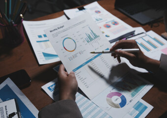 Fototapeta premium business people or accountant using calculator while working analytical business report on the workplace, accounting concept, Serious and focused financier accountant on paper work inside office,