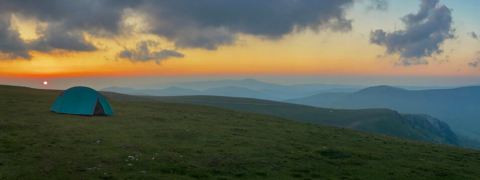 green camping tent at sunset on the summit of the carpathian mountains in Parang monts, Urdele , Romania