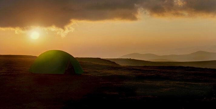green camping tent in sunny light at sunset in the carpathian mountains in Parang monts, Urdele