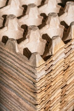 Stack of empty egg cartons made of recycled pulp paper. Sustainable packaging material storage and sorting process for ecological waste management and environmental protection.