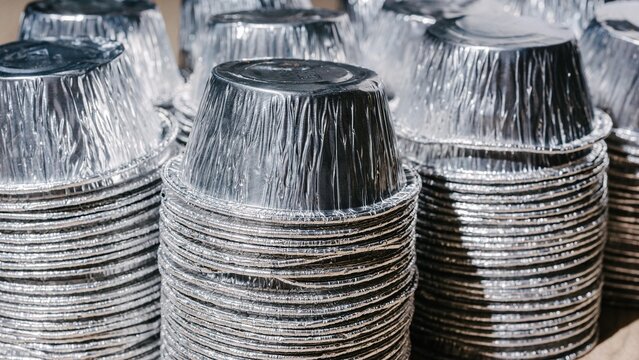 Stack of empty aluminum foil containers for food storage. Recyclable metal packaging for eco friendly waste management and garbage sorting. Industrial material for sustainability.