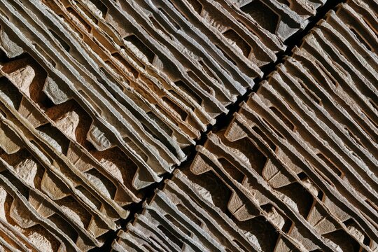 Stack of recycled cardboard egg cartons arranged in geometric pattern. Texture of waste paper material for industrial recycling process. Sustainable packaging and eco friendly material concept.
