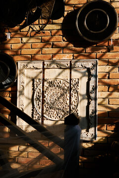 Vintage carved wall panel on rustic brick interior with dramatic sunlight and shadows display