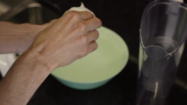 Changing water filter - Hands opening new water filter packaging and soaking filter in water bowl        