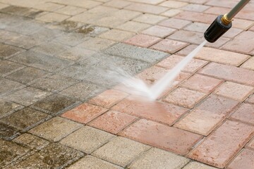 Obraz premium The Pressure Washer Cleaning Bricks With High Powered Water Jet On Pavement