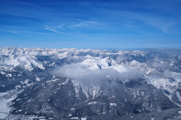 Fototapeta premium Stunning winter panoramic view of alpine mountain ranges above the clouds.