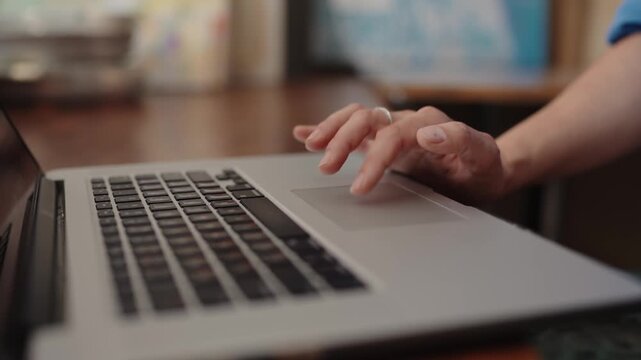 Close up view of a hand scrolling and using gestures on a laptop's trackpad with a shallow depth of field, Close-up view of a woman's hand using the touchpad on a laptop computer. tapping, scrolling.