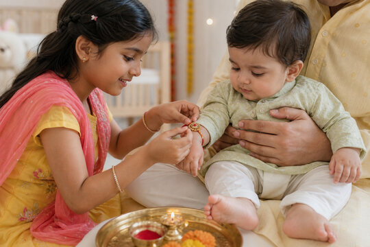 Little sister tying rakhi to baby brother during Raksha Bandhan
