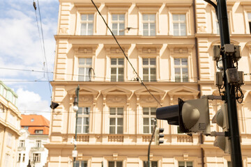 Classic multi-story beige stone building with tall rectangular windows and decorative cornices seen from a city street. Foreground shows a traffic signal © Alena