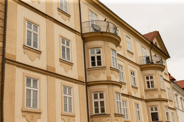 Fototapeta premium Beige historic apartment building facade featuring repeated sash windows, curved bay projections with iron rail balconies, decorative plaster moldings and a