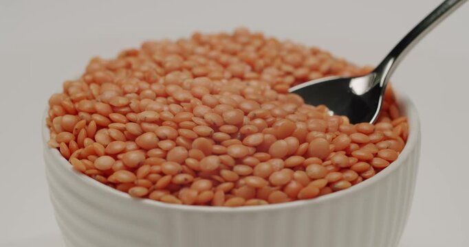 Raw organic red lentils rotating in a beautiful slow motion macro shot. Healthy eating concept with a background of protein-rich legumes, ideal for vegan and vegetarian diets and cooking shows.