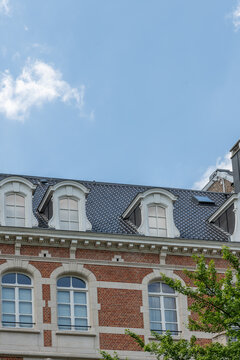 Brussels, Belgium. Historic Belgian townhouse with dormer windows beneath expansive blue summer sky in Ixelles