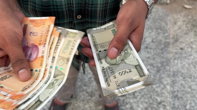 Close up shot of an Indian man counting cash outdoors, male hands holding and counting Indian currency cash, finance and investment concept