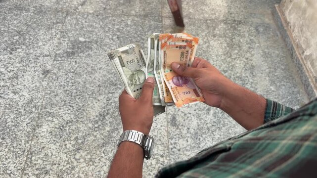 Close up shot of an Indian man counting cash outdoors, male hands holding and counting Indian currency cash, finance and investment concept